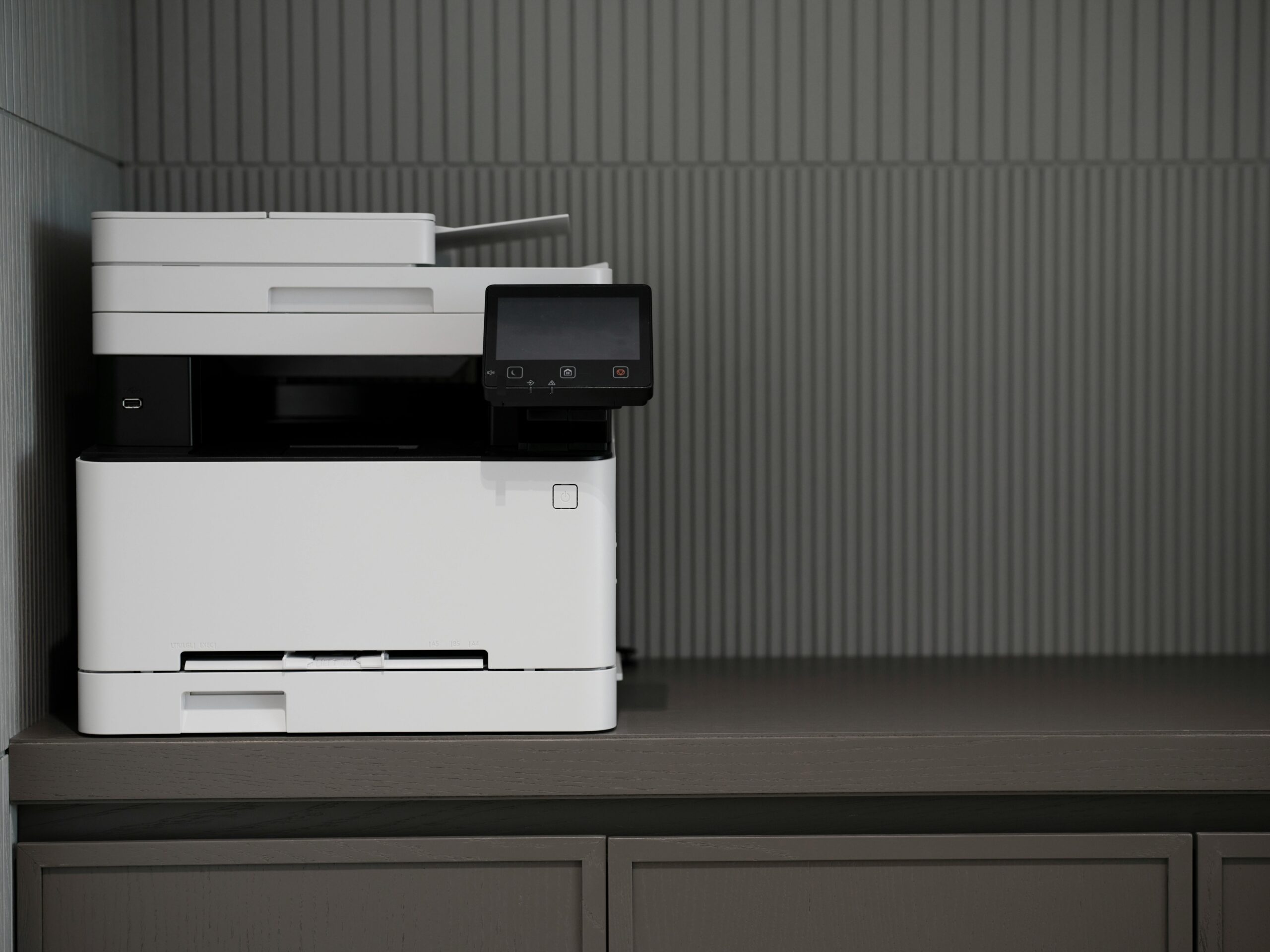 A sleek, modern printer situated on a minimalist office desk with a textured background.